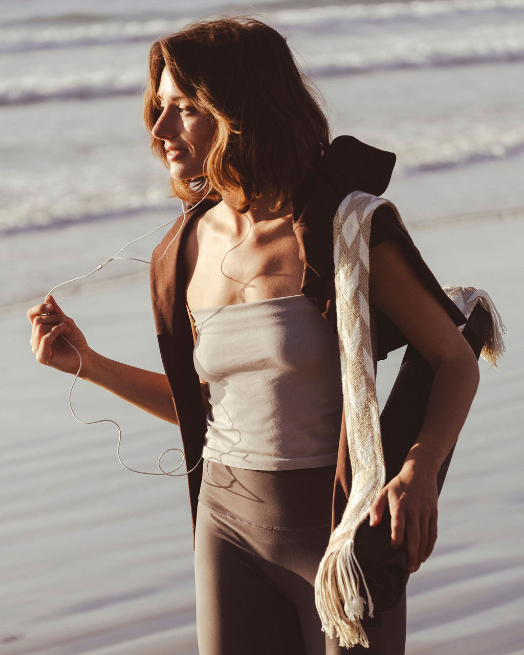Woman holding yoga mat strap at the beach